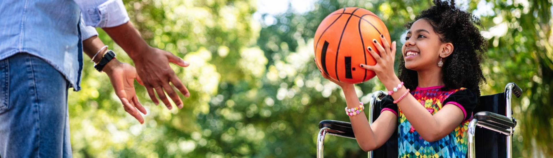 petite fille en fauteuil roulant jouant au basket 